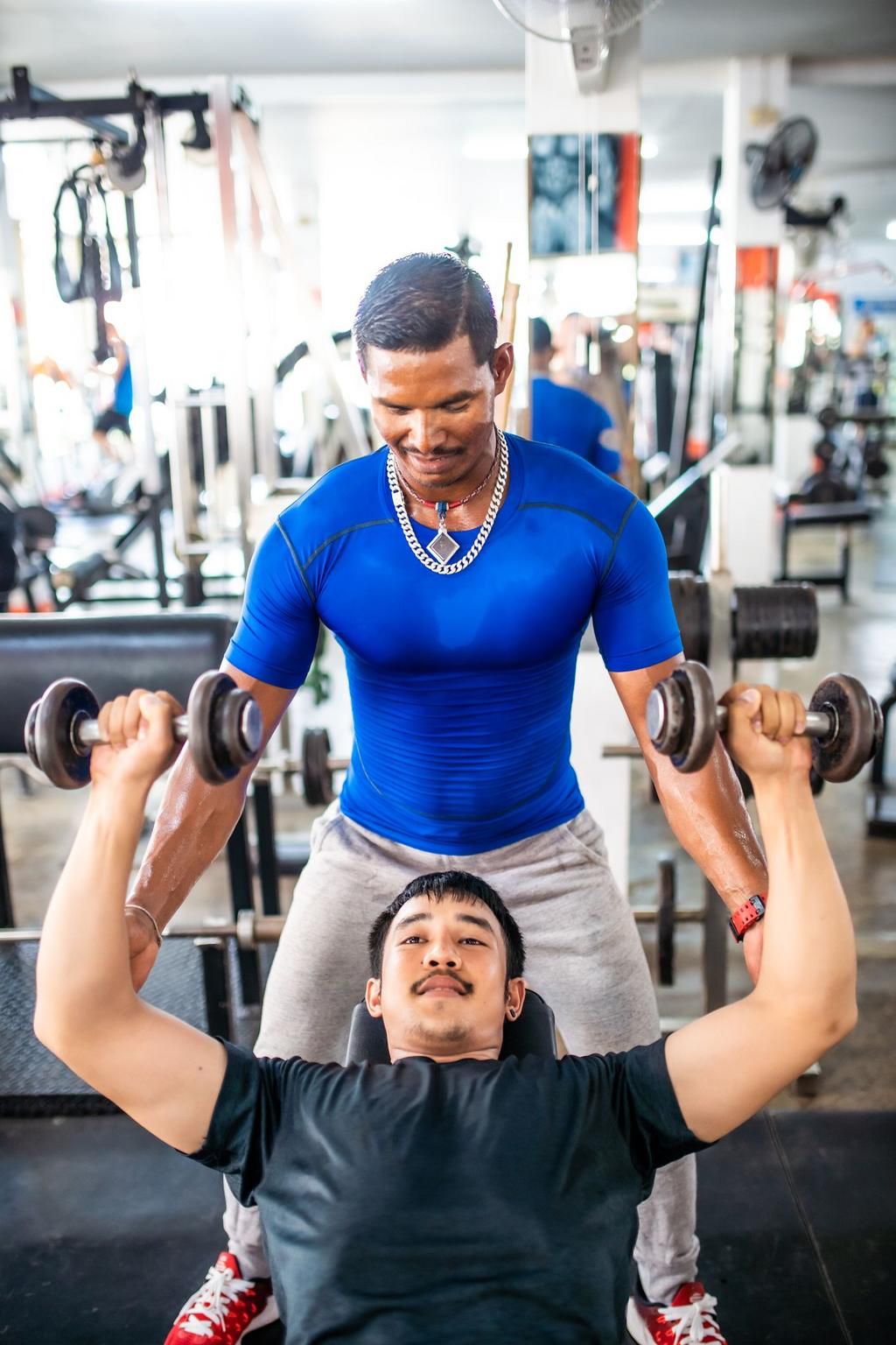 Personal trainer explaining how to exercise with dumbbells at the gym