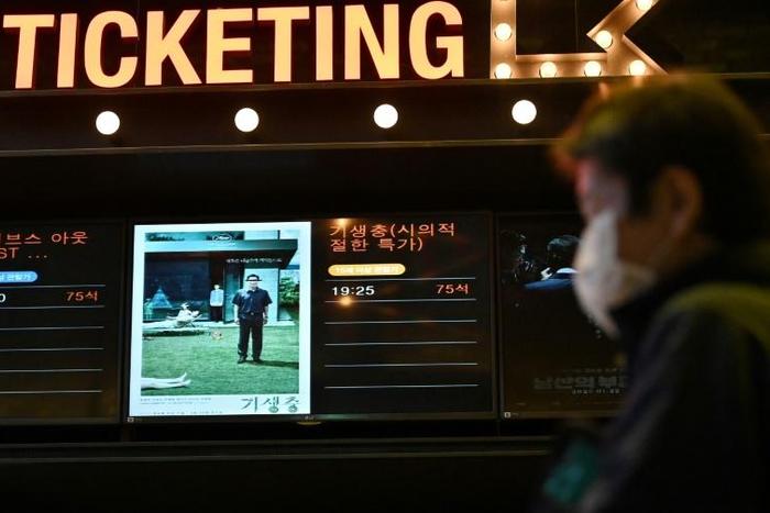 A man walks past a screen showing a poster of Bong Joon-ho's film 'Parasite' at a cinema in Seoul on the day the movie won the Oscar for best picture