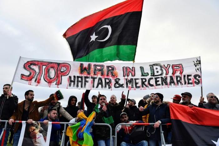 Protesters hold a banner reading "Stop war in Libya, Haftar and mercenaries" during a protest near the chancellery during the Peace summit on Libya at the Chancellery in Berlin on January 19, 2020
