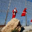 Palestinian children wearing Santa Claus costumes play near Israel's separation barrier west of Bethlehem in the occupied West Bank