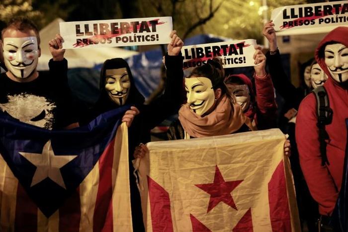 Demonstrators wear Guy Fawkes masks, hold Catalan pro-independence "Estelada" flags and placards reading "Freedom for Political Prisoners" during a "Million Mask March" organised by Anonymous and other movements this week