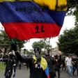 Protestors with their faces covered wave flags during a demonstration against the government of Colombia’s President Ivan Duque in Bogota
