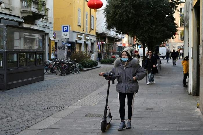 A woman wearing a mask walks in Via Paolo Sarpi, the commercial street in a Chinese district of Milan