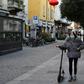A woman wearing a mask walks in Via Paolo Sarpi, the commercial street in a Chinese district of Milan