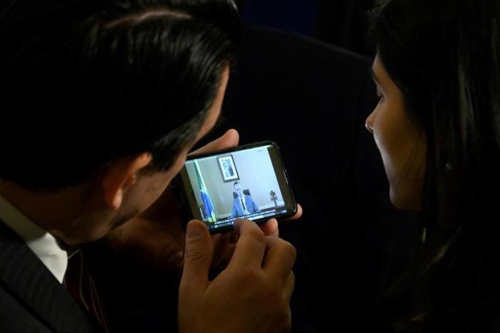 At a gathering of the Organization of American States (OAS) in Washington, two people watch a phone showing a speech by Brazil's culture secretary Roberto Alvim in which he was accused of quoting Joseph Goebbels