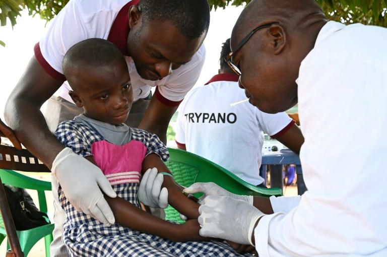 A health worker takes blood from a child in the Ivorian village of Paanenefla - The sample will be tested for sleeping sickness