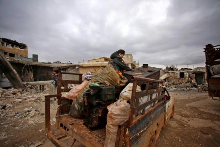 Syrians flee with belongings that they salvaged from the rubble of their home levelled by an air strike on the west Aleppo village of Kafr Nuran