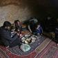 Darra lays down a large carpet for the family to share a frugal meal on the bare earth of the underground shelter
