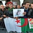 People stand with national flags and portraits of Gaid Salah as they gather outside the People's Palace during his funeral in Algiers