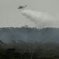 A helicopter dumps water on a bushfire in the outer suburbs of Melbourne