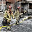 Firefighters walk past destroyed houses after the explosion of a gas tanker in Lima left at least eight people dead and dozens injured