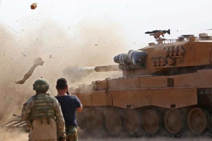 Turkish soldiers at a position east of Ras al-Ain watch as a tank fires on positions held by Kurdish-led forces