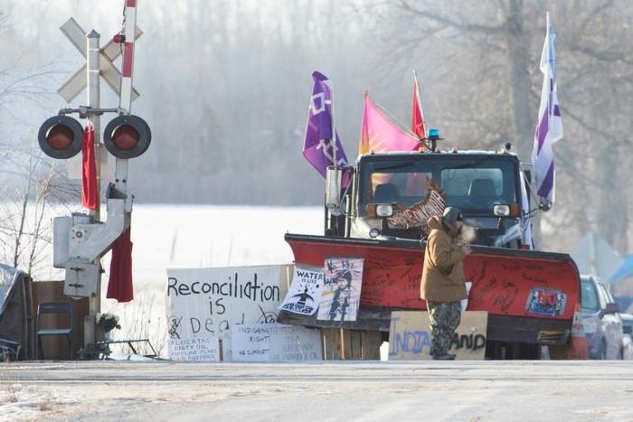 A First Nations protester walk in front of a snow plow blade that has signatures from the  Wetʼsuwetʼen hereditary chiefs as part of a train blockade in Tyendinaga, near Belleville, Ontario, Canada on February 21, 2020