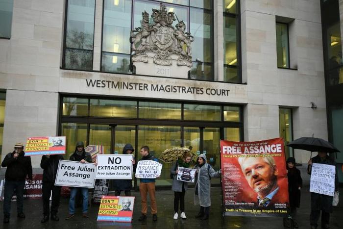Supporters wave banners outside the London court where WikiLeaks founder Julian Assange was testifying about how he was spied on inside the Ecuadoran embassy