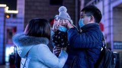 Parents put a protective mask on their baby outside Beijing railway station ahead of the Lunar New Year. State media has reported that a baby tested positive for the virus just 30 hours after being born