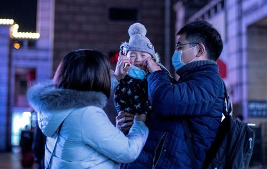 Parents put a protective mask on their baby outside Beijing railway station ahead of the Lunar New Year. State media has reported that a baby tested positive for the virus just 30 hours after being born