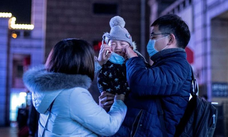 Parents put a protective mask on their baby outside Beijing railway station ahead of the Lunar New Year. State media has reported that a baby tested positive for the virus just 30 hours after being born