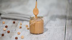 Hazelnut butter in a glass jar on a wooden table.