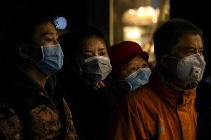 People wearing protective facemasks queue for food in Shanghai