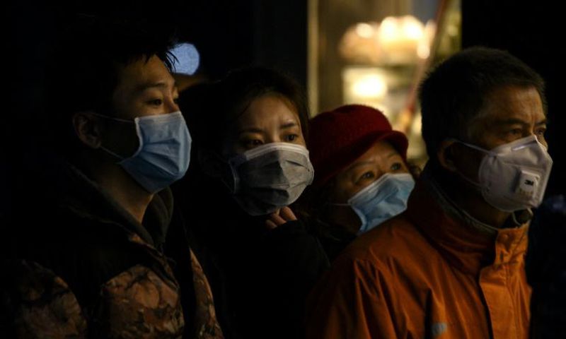 People wearing protective facemasks queue for food in Shanghai