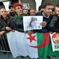People stand with national flags and portraits of Algeria's late military chief Lieutenant general Ahmed Gaid Salah as they gather outside the People's Palace during his funeral in Algiers on Wednesday