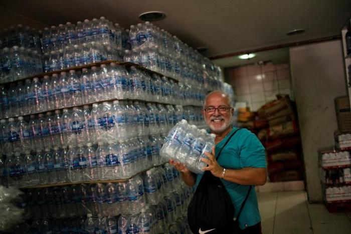 A man smiles after finding bottled water on sale in a liquor store in  Rio de Janeiro on January 15, 2020