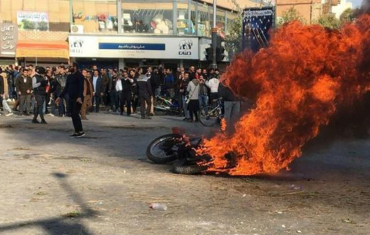 Iranian protesters gather around a burning motorcycle in the city of Isfahan during a demonstration last month against an increase in fuel prices