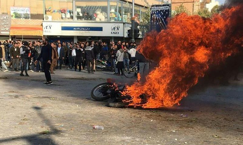 Iranian protesters gather around a burning motorcycle in the city of Isfahan during a demonstration last month against an increase in fuel prices