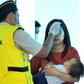 An Indonesian health official checks the temperature of passengers at the airport in Palu, Central Sulawesi. Indonesia has not reported any confirmed infections so far