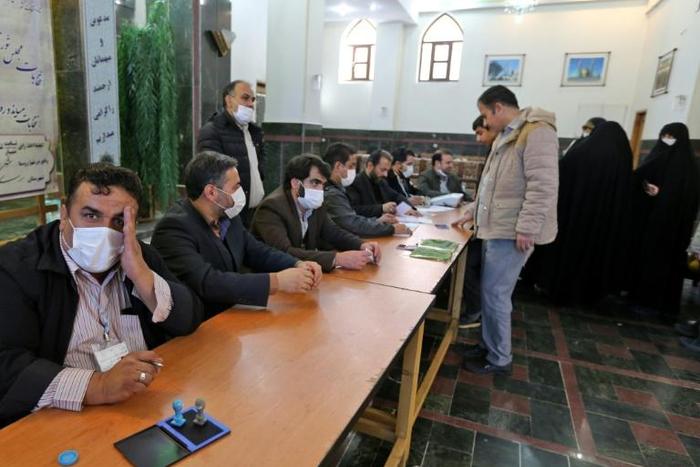 Organisers wear masks as they oversee voting in Iran's Friday parliamentary election days after the coronavirus outbreak first emerged