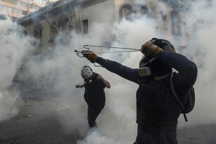 A demonstrator aims a sling at the police during a protest against Chilean President Sebastian Pinera's government in Santiago