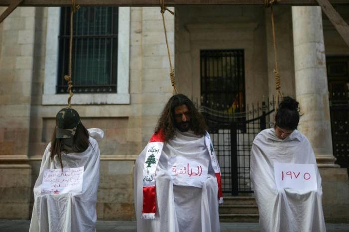Lebanese protesters stage a mock hanging in a symbolic performance against sectarianism (C), Lebanon's 1975-90 civil war (R) and corruption during ongoing anti-government demonstrations in Beirut on November 3, 2019
