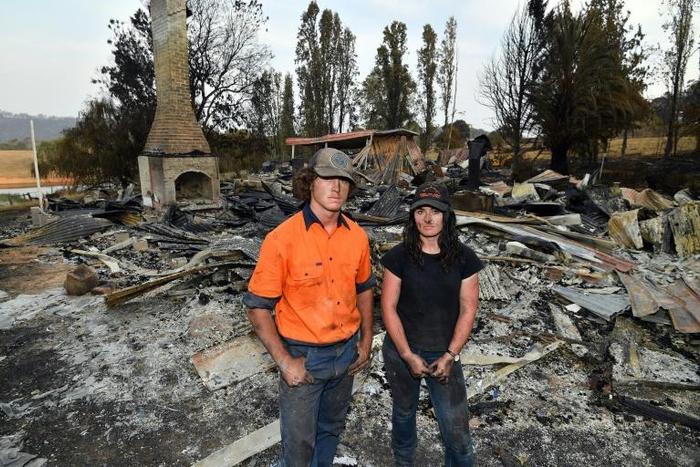 Brother and sisters Jesse and Kiahan Bellchambers stand in front of the charred ruins of their home in Batlow, in Australia's New South Wales state