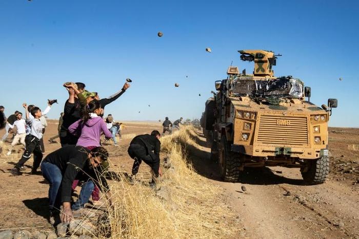 A small group of people pelted the convoy with rocks and shoes as it drove by near the town of Maabda, close to the Turkish border
