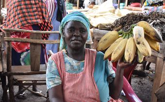 Jennifer Nagut from Maero village in Uganda displays the bananas at her stall in Busia, Kenya. She is among several Ugandan women who cross the border every day to sell nutritious foodstuffs to Kenya | Photo by Faith Matete
