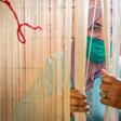A Moroccan rug weaver peeks from behind carpet thread at a workshop in the city of Sale, north of the capital Rabat