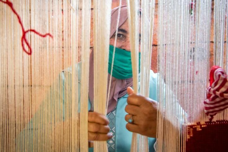 A Moroccan rug weaver peeks from behind carpet thread at a workshop in the city of Sale, north of the capital Rabat