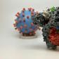 A 3D print of a spike protein of SARS-CoV-2, the virus that causes COVID-19 -- in front of a 3D print of a SARS-CoV-2 virus particle