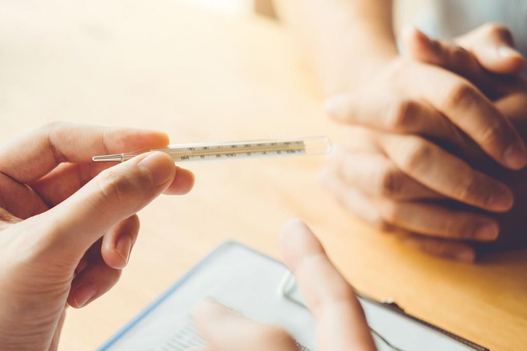 Cropped Hands Of Male Doctor Holding Thermometer With Male Patient In Hospital