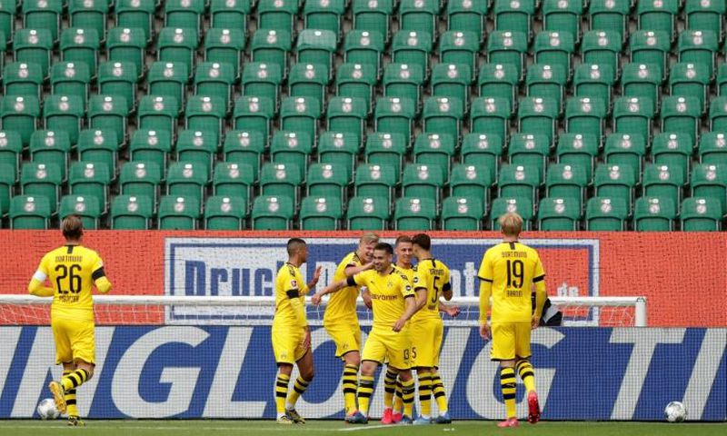 Raphael Guerreiro (C) celebrates scoring the opening goal in Borussia Dortmund's 2-0 win at Wolfsburg in a near-empty stadium.