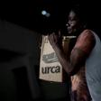 A woman in Rio de Janeiro's City of God favela carries a box with donations of basic food supplies distributed by an NGO to people suffering economic hardship during the novel coronavirus in Brazil