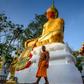 A monk walks in front of a giant Buddha statue wearing a face mask at Wat Nithet Rat Pradit temple in Pathum Thani outside Bangkok