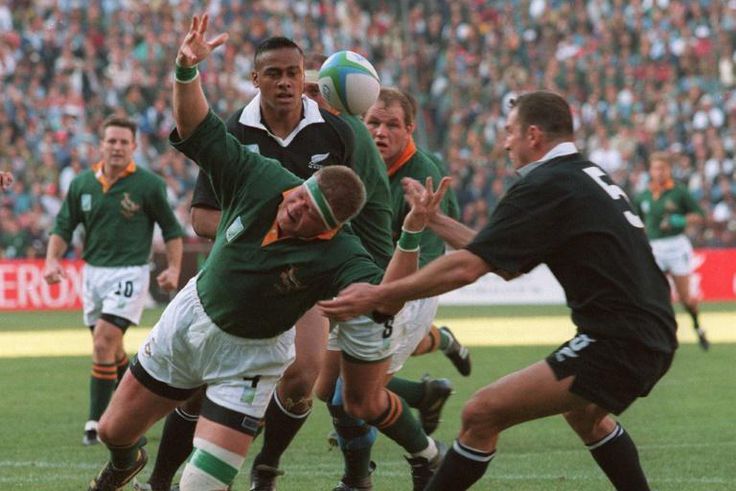 Springbok Kobus Wiese (C) loses the ball as he falls between All Blacks Jonah Lomu (behind) and Robin Brooke (R) during the 1995 Rugby World Cup final  in Johannesburg
