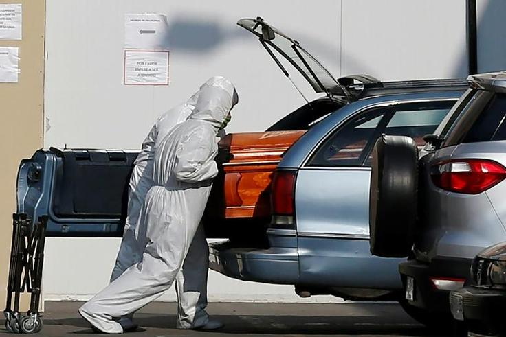 Employees of a Santiago funeral parlour load a coffin of a person who died of COVID-19 into a relative's vehicle outside the San Jose Hospital -- the Chilean capital has borne the brunt of the country's outbreak