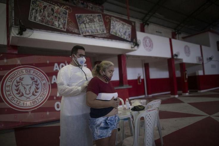 A doctor examines a woman showing symptoms of the novel coronavirus, COVID-19, during a day of free health checks at a samba school in Rio de Janeiro, Brazil, on May 24, 2020