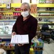Shop owner Mudaver Uygur shows the book where he notes money owed him by costumers -- wealthier ones have stepped into the breach to pay off debts worth hundreds of dollars in some cases