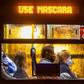 Commuters wearing face masks travel on a public bus with an electronic sign reading "Wear a face mask", in Curitiba, Brazil on May 22, 2020