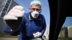 German doctor Michael Grosse takes a sample from a car driver at a drive-through testing point for the coronavirus in Halle, eastern Germany