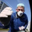 German doctor Michael Grosse takes a sample from a car driver at a drive-through testing point for the coronavirus in Halle, eastern Germany