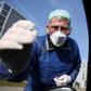 German doctor Michael Grosse takes a sample from a car driver at a drive-through testing point for the coronavirus in Halle, eastern Germany